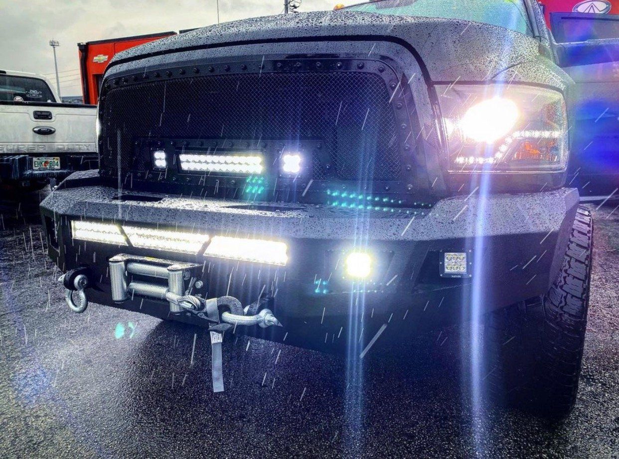 A black truck is parked in the rain with its lights on. | CB Wheels & Tires, 4x4, Suspension, Center