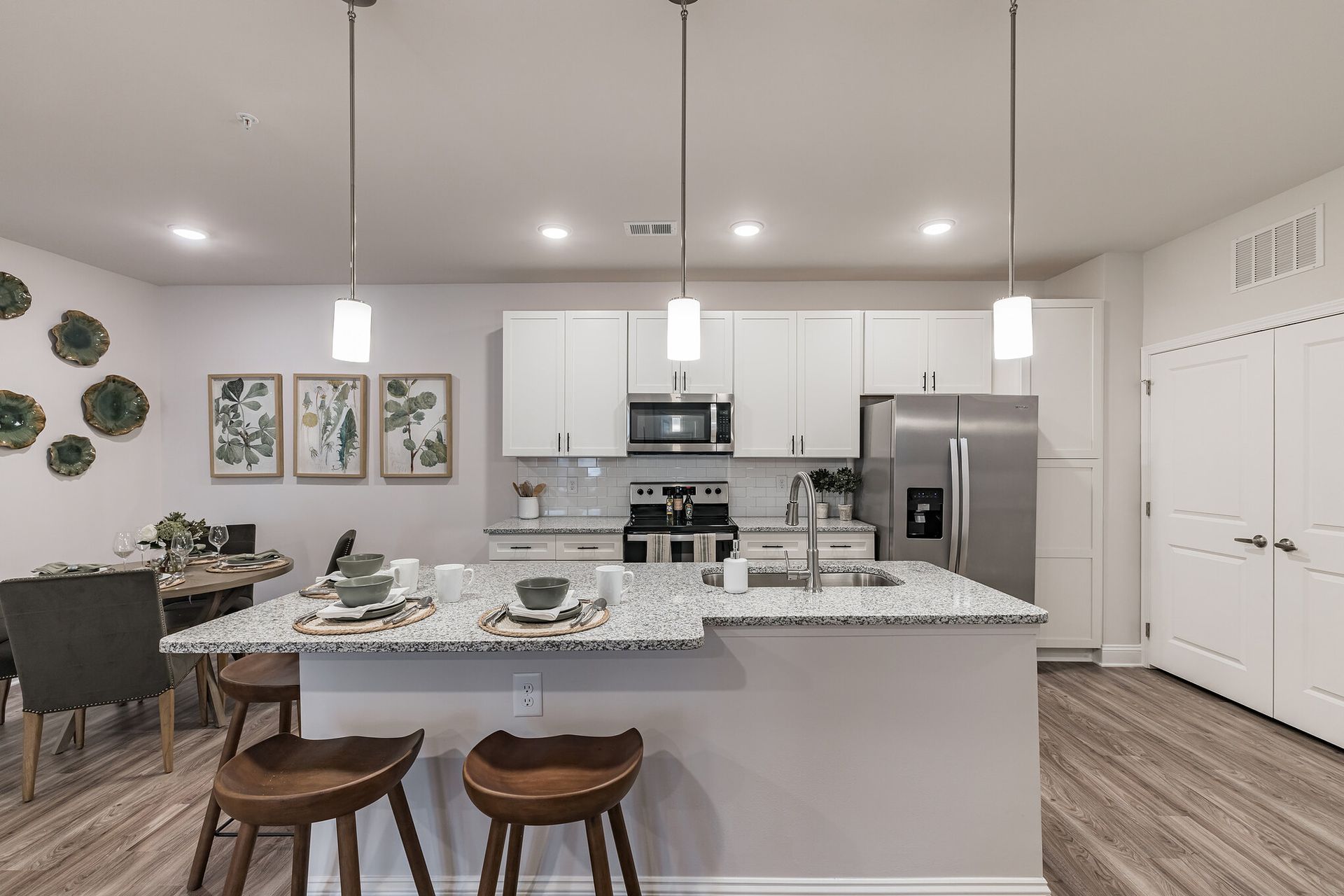 A kitchen with white cabinets , stainless steel appliances , granite counter tops and a large island at The Standard at Pinestone. 