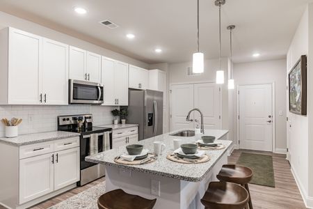 A kitchen with white cabinets , granite counter tops , stainless steel appliances and a large island.