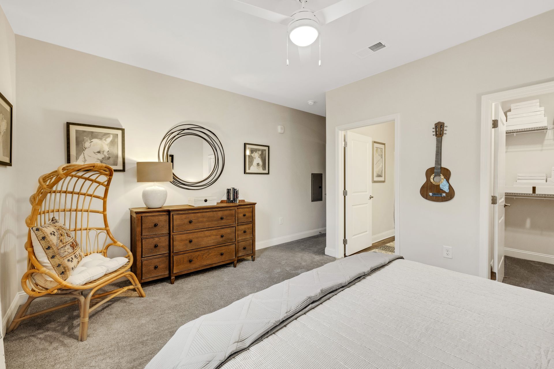 A bedroom with a bed , dresser , chair and guitar on the wall at The Standard at Pinestone. 
