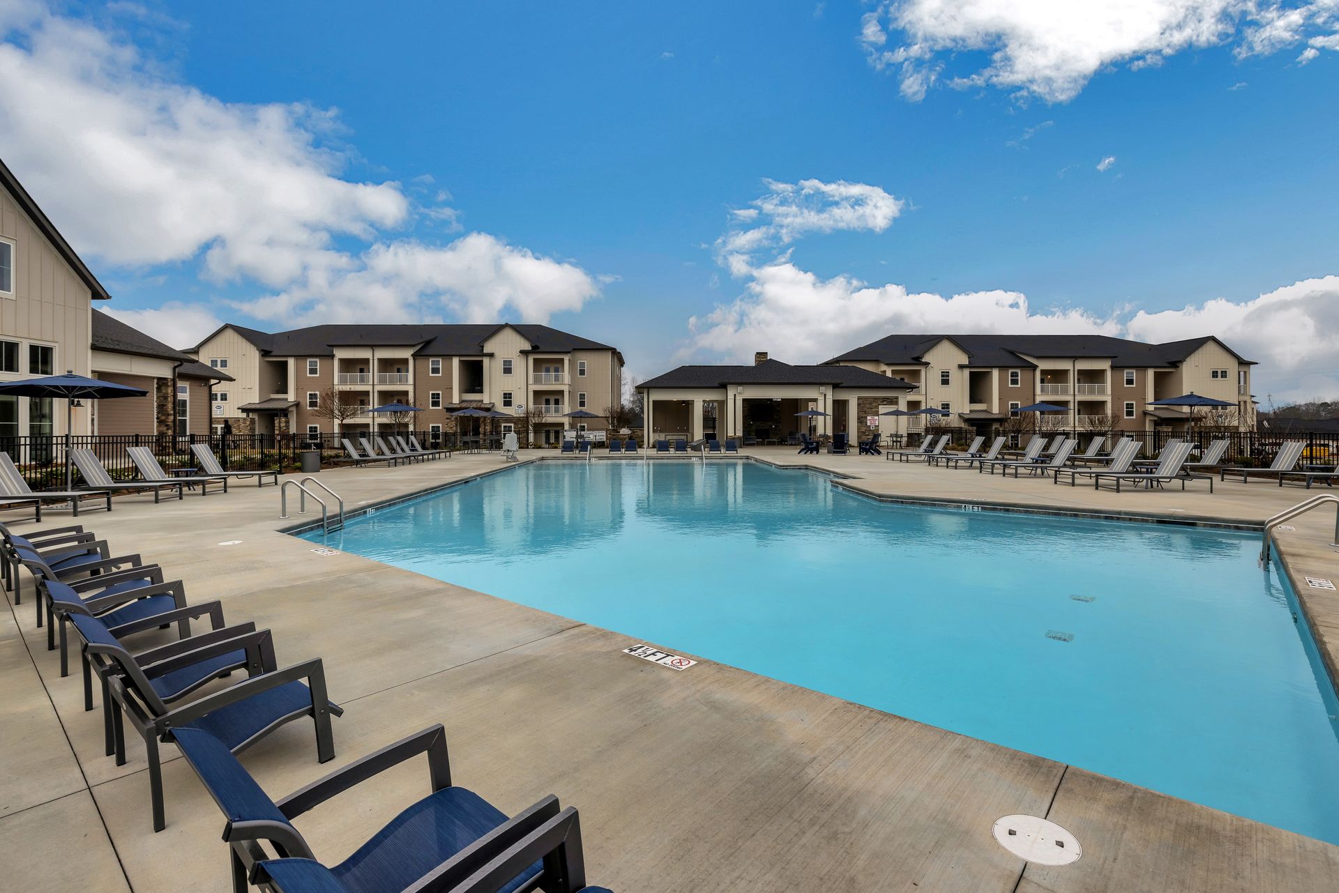 A large swimming pool surrounded by chairs and a building at The Standard at Pinestone. 