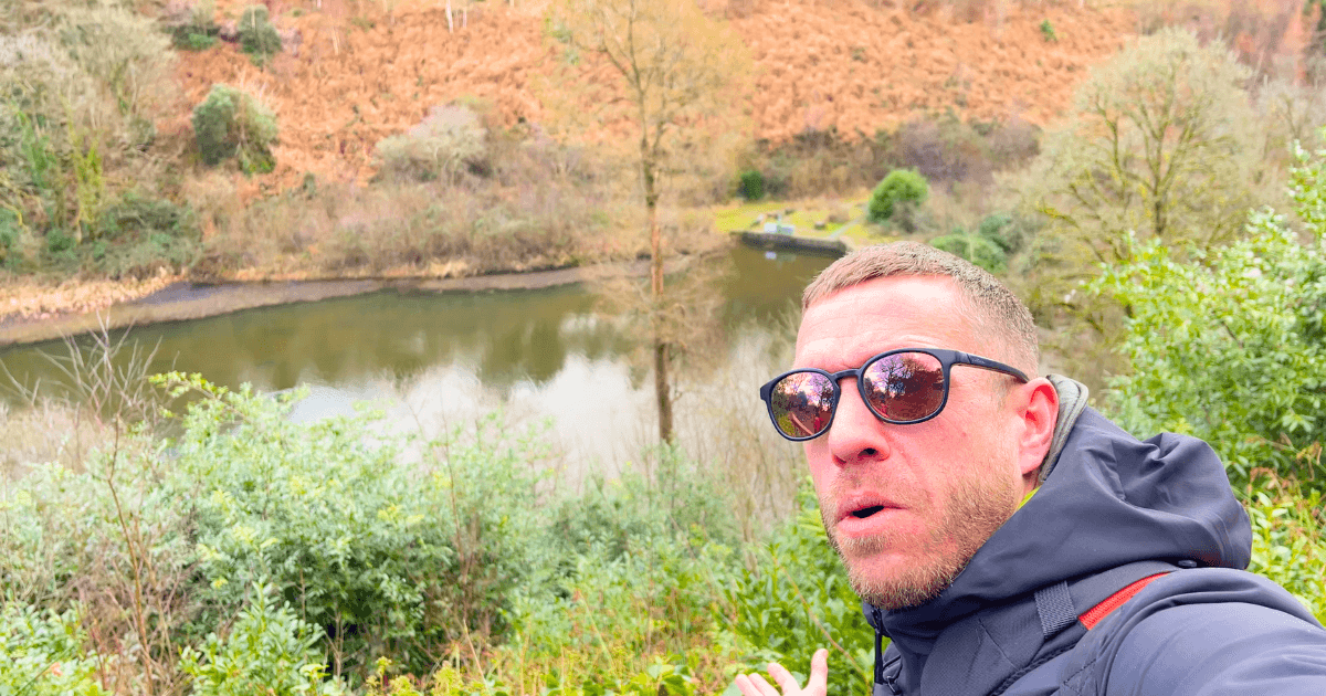 Trist wearing sunglasses is taking a selfie in front of a lake.