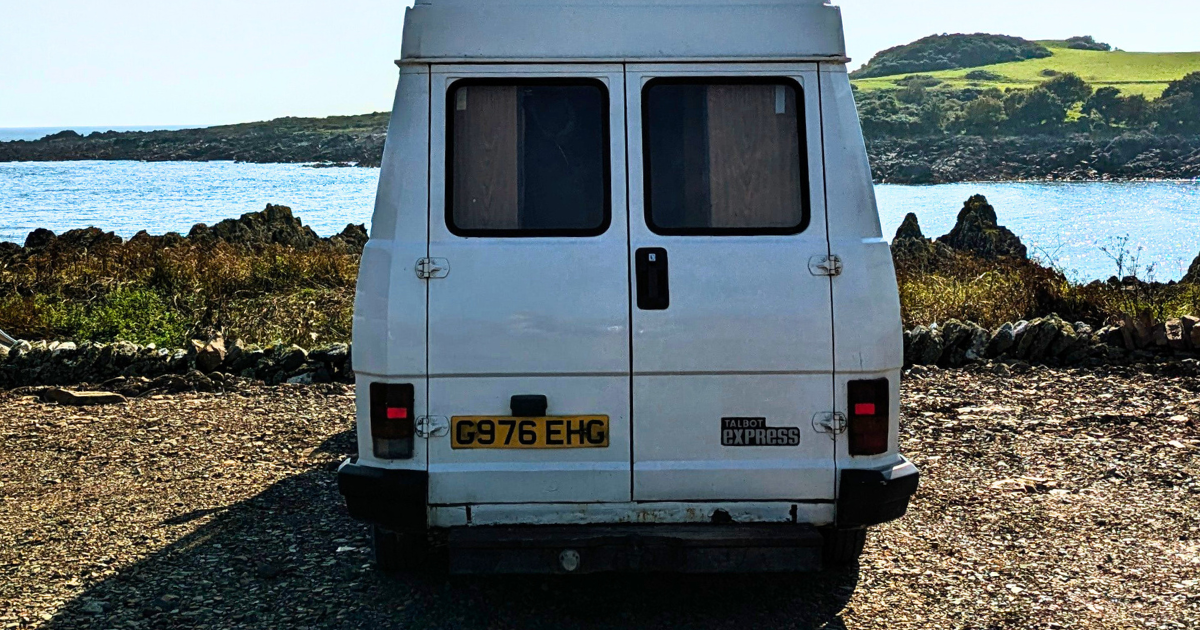 A white van is parked in front of a body of water.