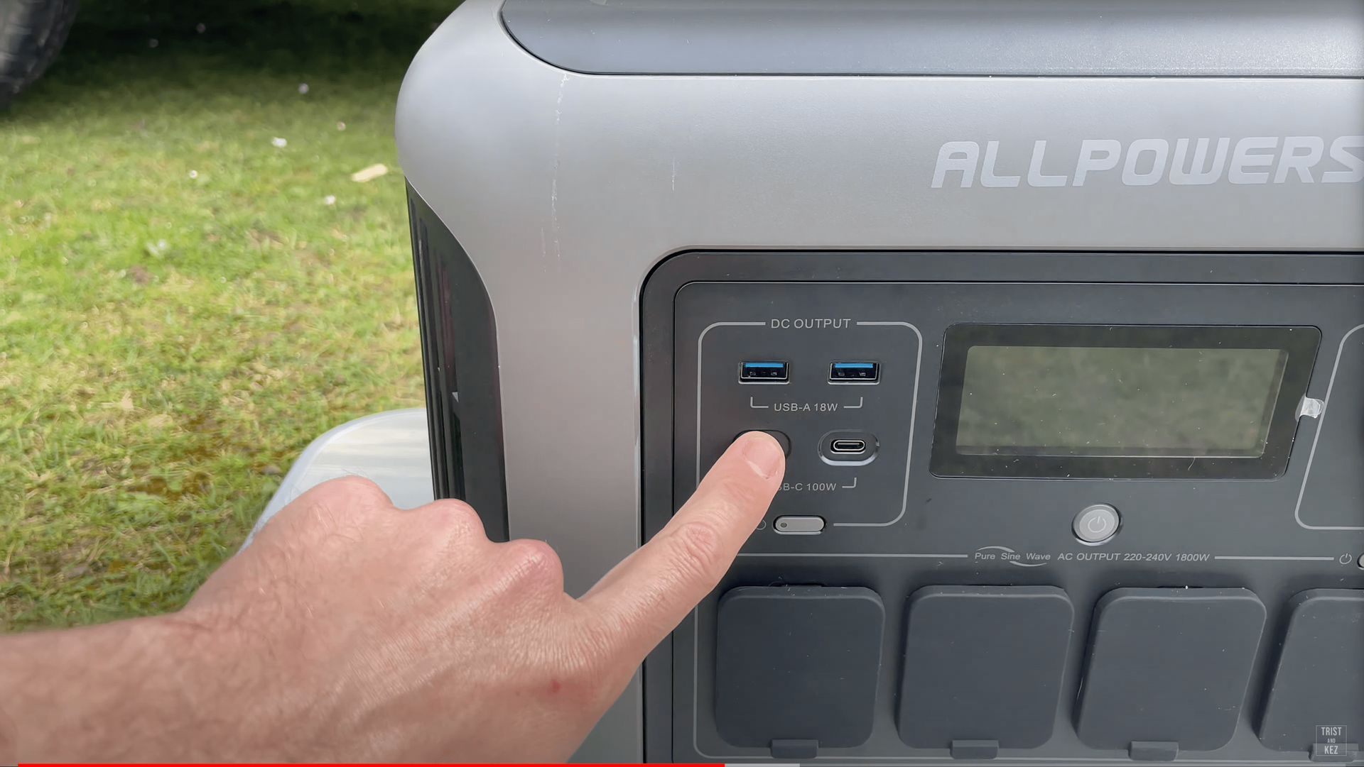 A person is pointing at a button on a portable power station.