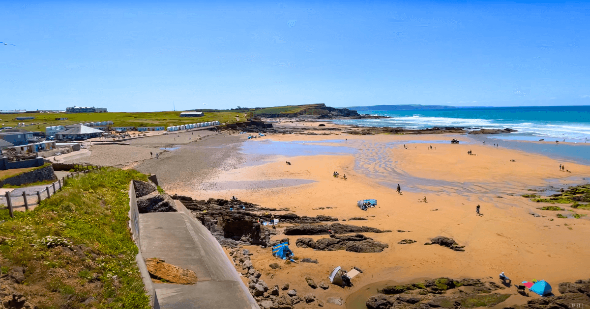 a beach with a lot of people on it and a blue sky in the background.