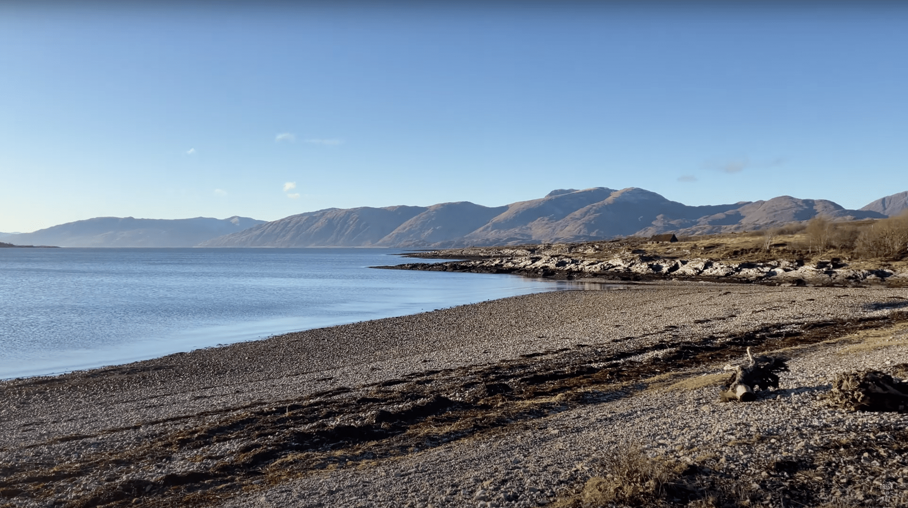 Cuil Bay beach with mountains in the background and Loch Linnhe in the foreground.