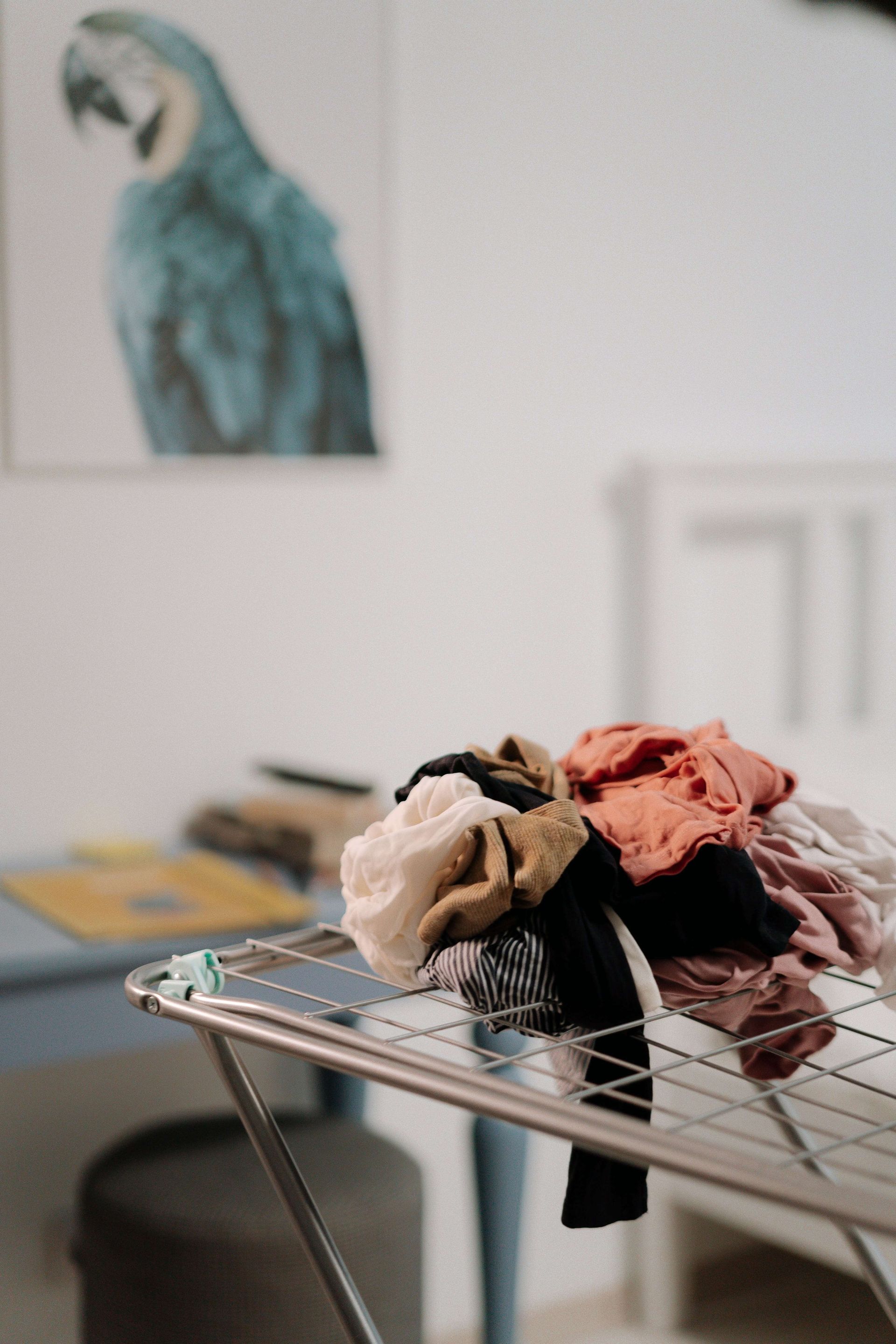 a pile of clothes is sitting on a clothes drying rack in a living room .