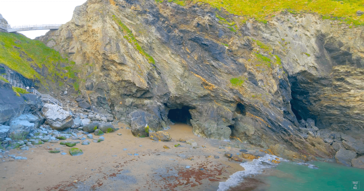 an aerial view of Merlin's cave on the shore of a beach.