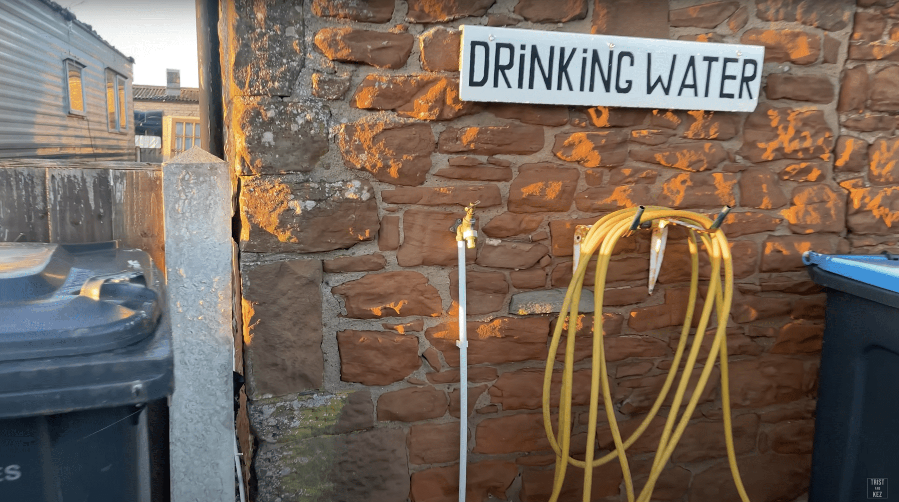 a hose is hanging on a brick wall next to a sign that says drinking water .