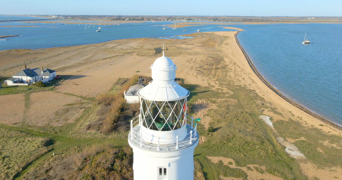 An aerial view of a lighthouse on a small island in the middle of the ocean.