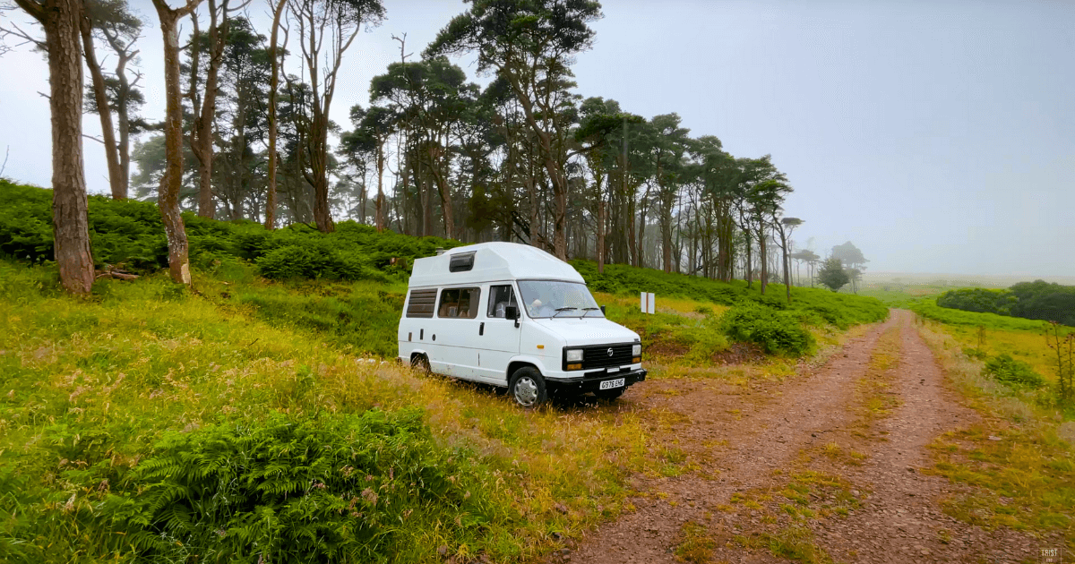 a white van is parked on the side of a dirt road in a field.