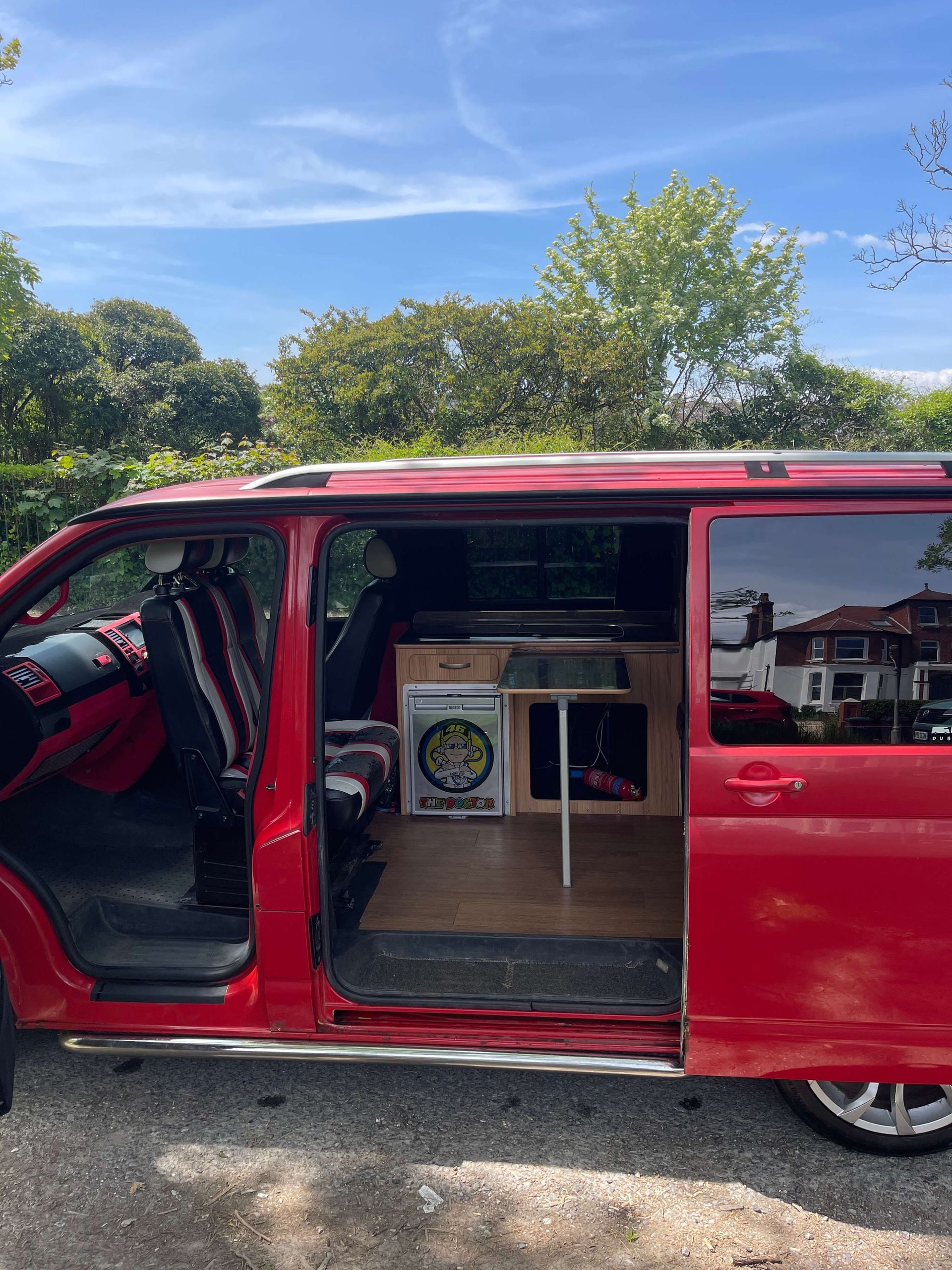 a red van with the doors open is parked in a parking lot.