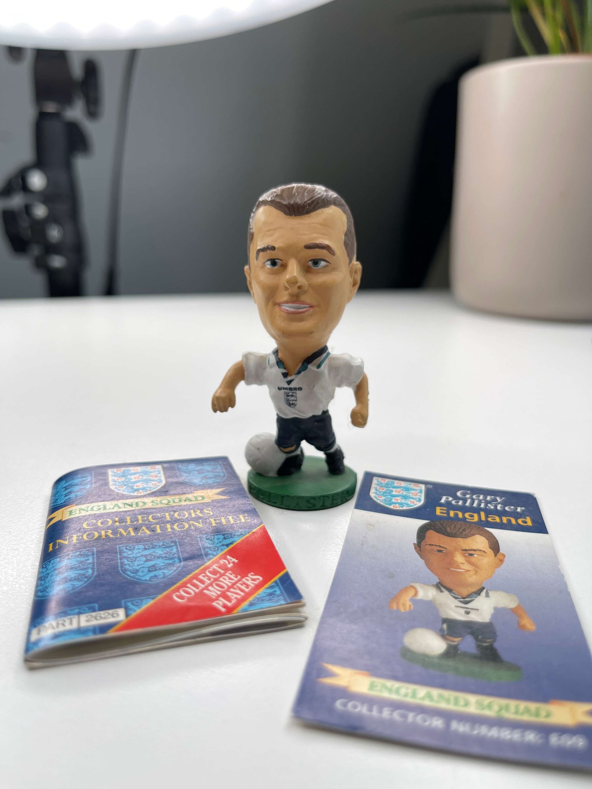 a soccer player figurine is sitting on a table next to a book .