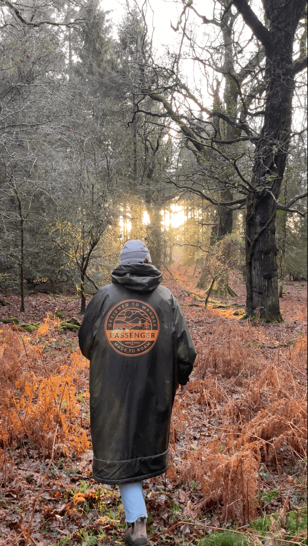 A person in a jacket is walking through a forest.