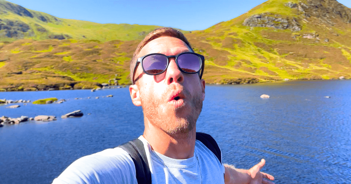 Trist wearing sunglasses is standing in front of a lake.