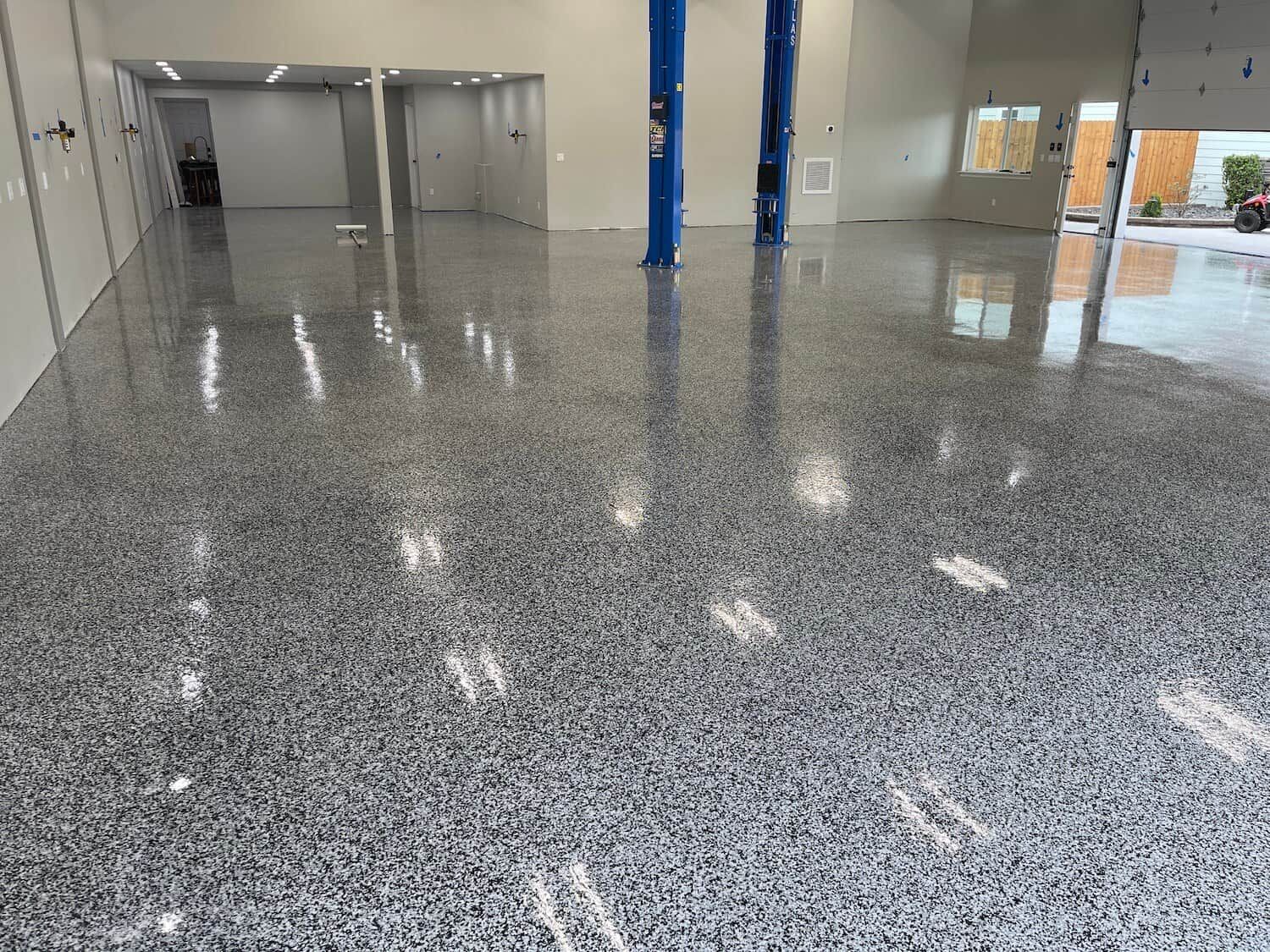A large room with a shiny floor and a lift in the background.