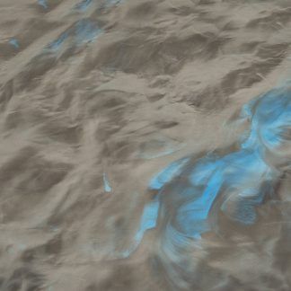 A close up of a sandy beach with a blue glow in the dark.