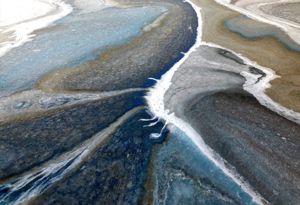 A close up of a painting of a river flowing through a rocky area.