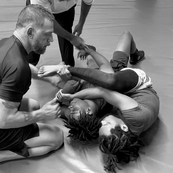A group of people are wrestling on a mat in a black and white photo.