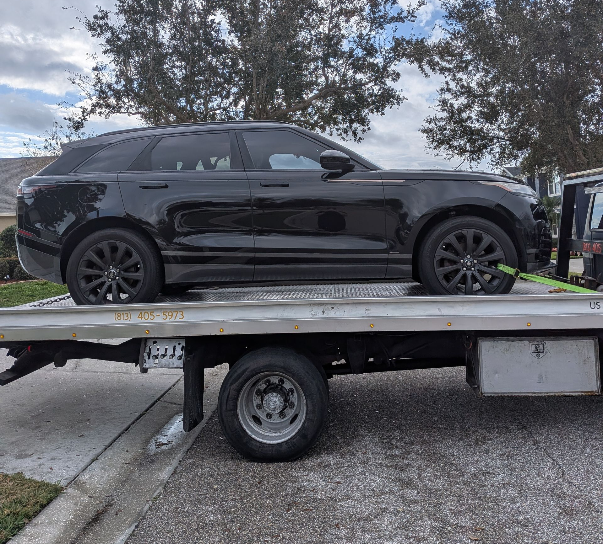 Professional flatbed towing service by Riverview Towing, safely hauling an SUV in a residential area of Riverview, Florida.