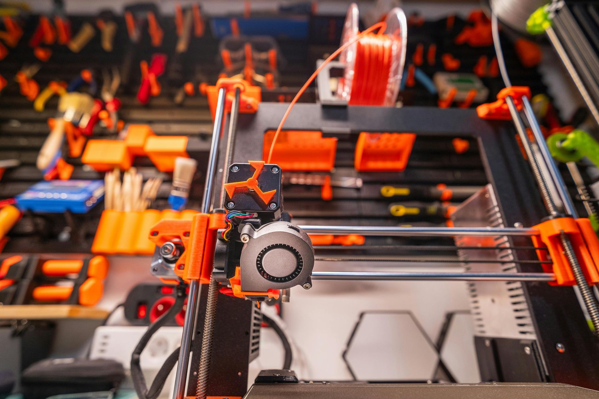 A 3d printer is sitting on top of a table surrounded by tools.