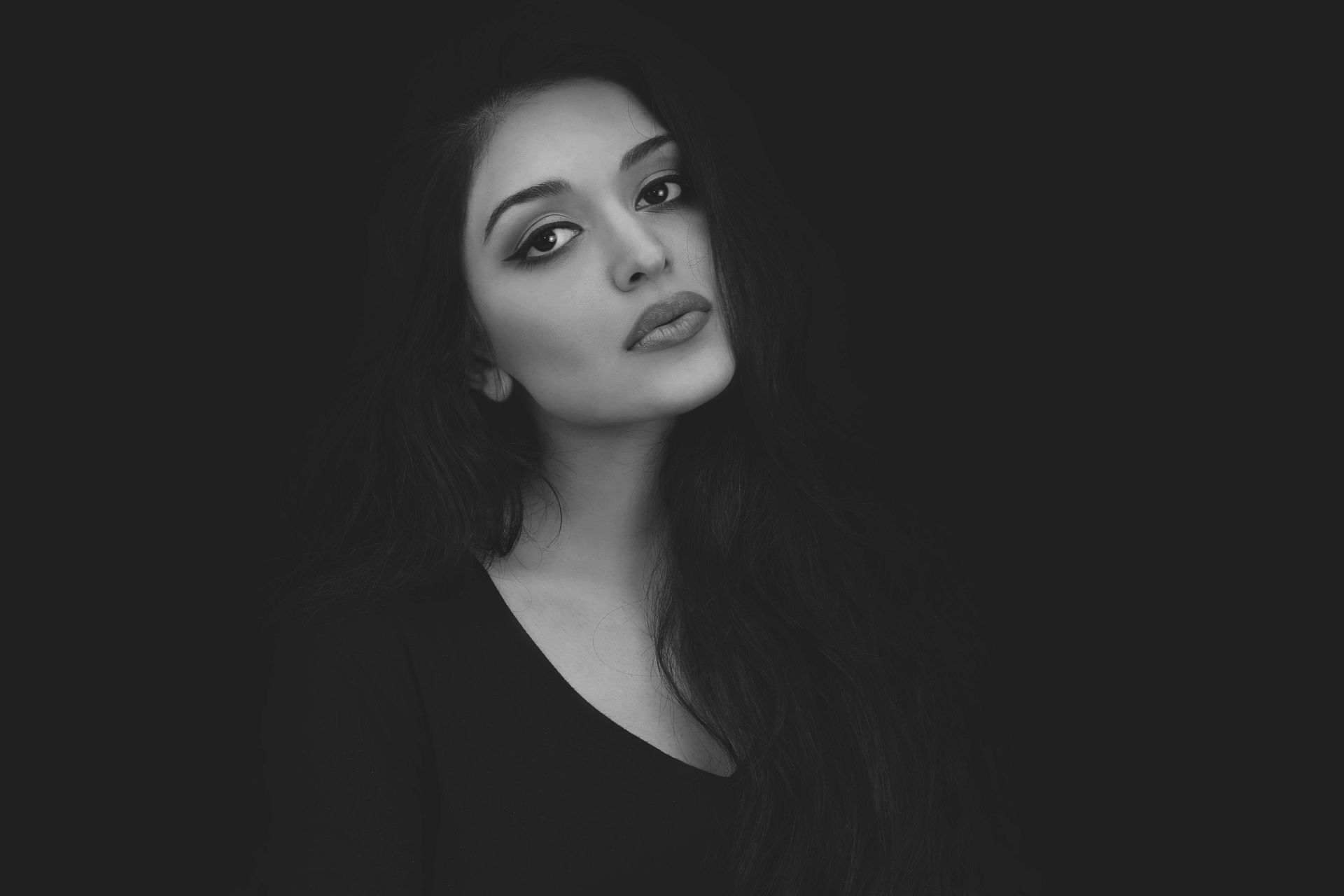 A black and white photo of a woman with long hair looking at the camera.