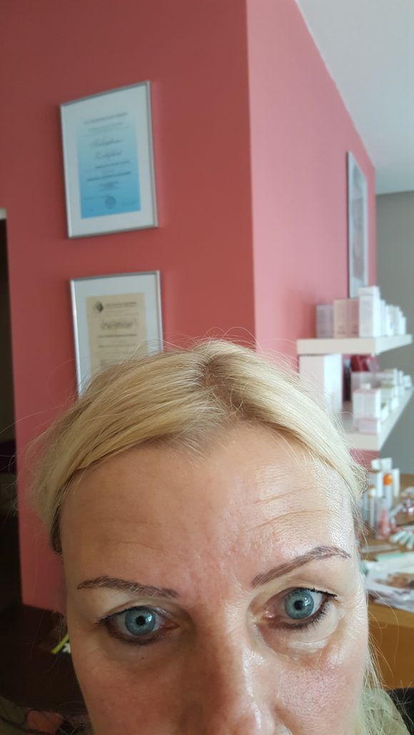 Eine Frau mit blonden Haaren und blauen Augen schaut in die Kamera.