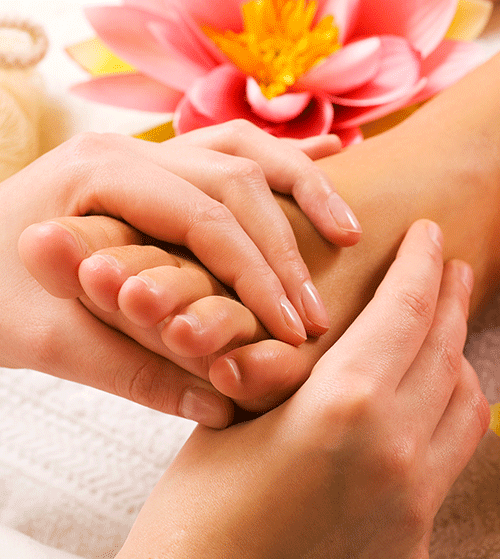 Eine Frau bekommt eine Fußmassage mit einer Blume im Hintergrund