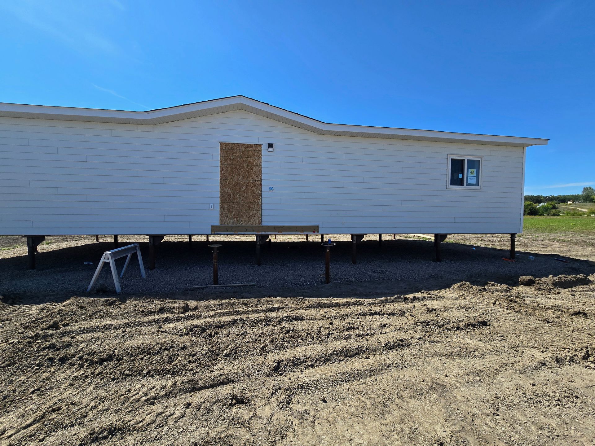 Hands hammering siding onto a house. Beige siding and a green long-sleeved shirt are visible.