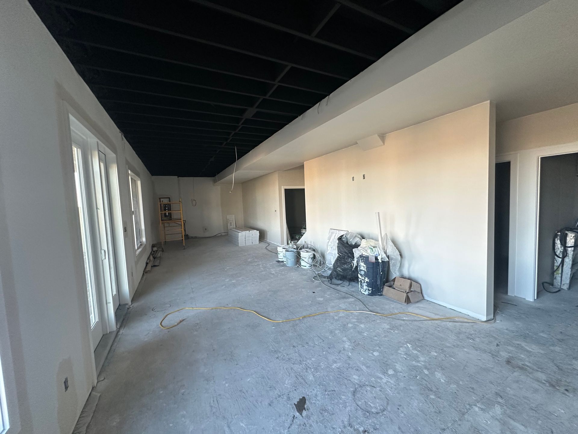 House under construction with scaffolding, workers on roof, chimney, brown siding, sunny day.