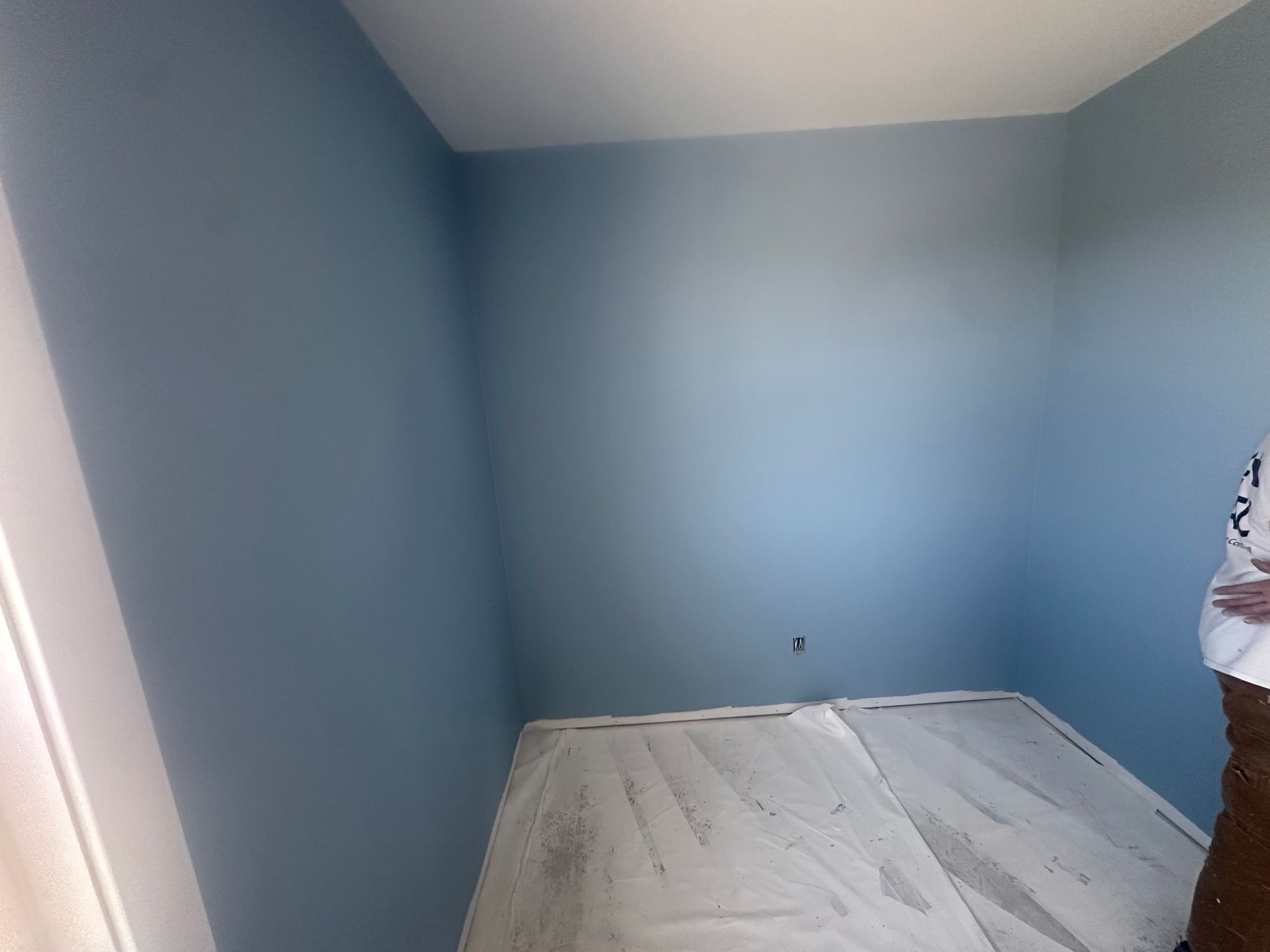 Person wearing a glove, installing drywall.