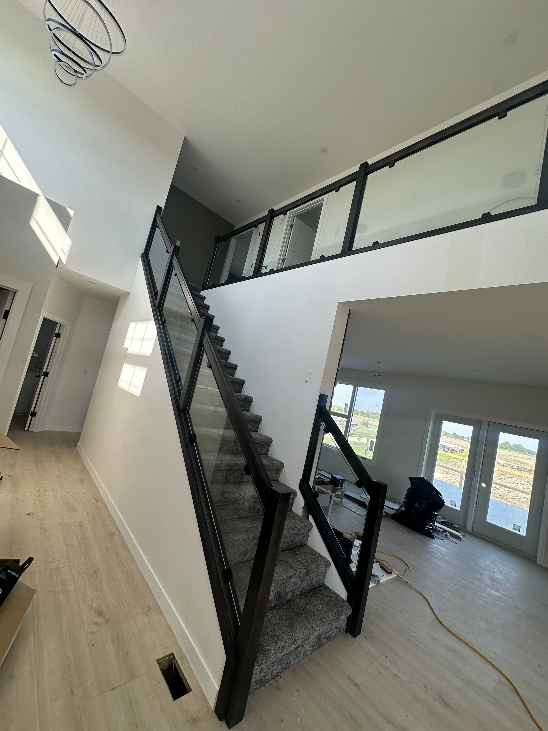 Wooden staircase with dark banister, descending into a room with light-colored walls and wood floors.