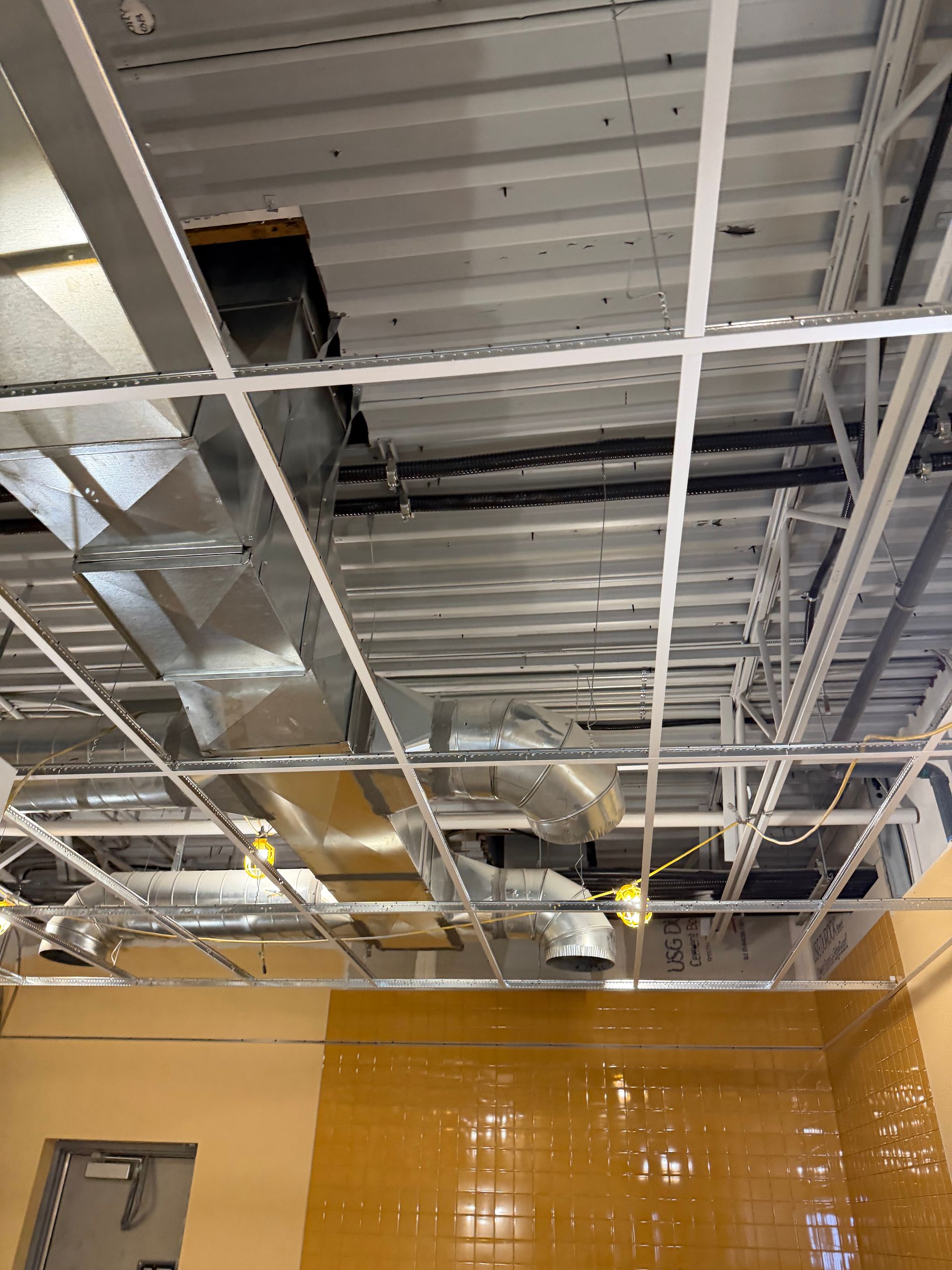Metal air ducts snaking across a ceiling, reflecting blue light.