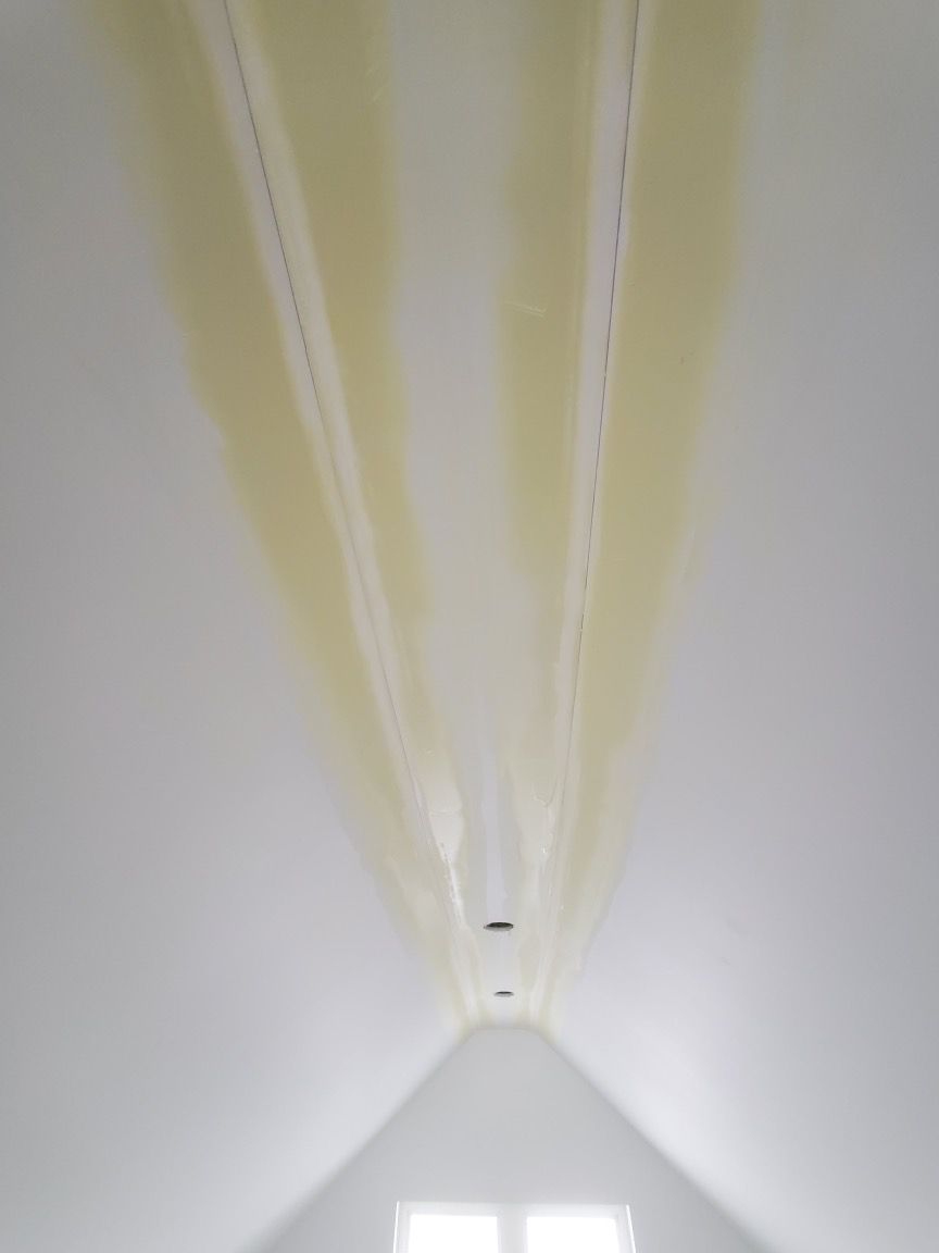 Attic bedroom with angled ceiling, wood floor, bed, and workspace by the window.