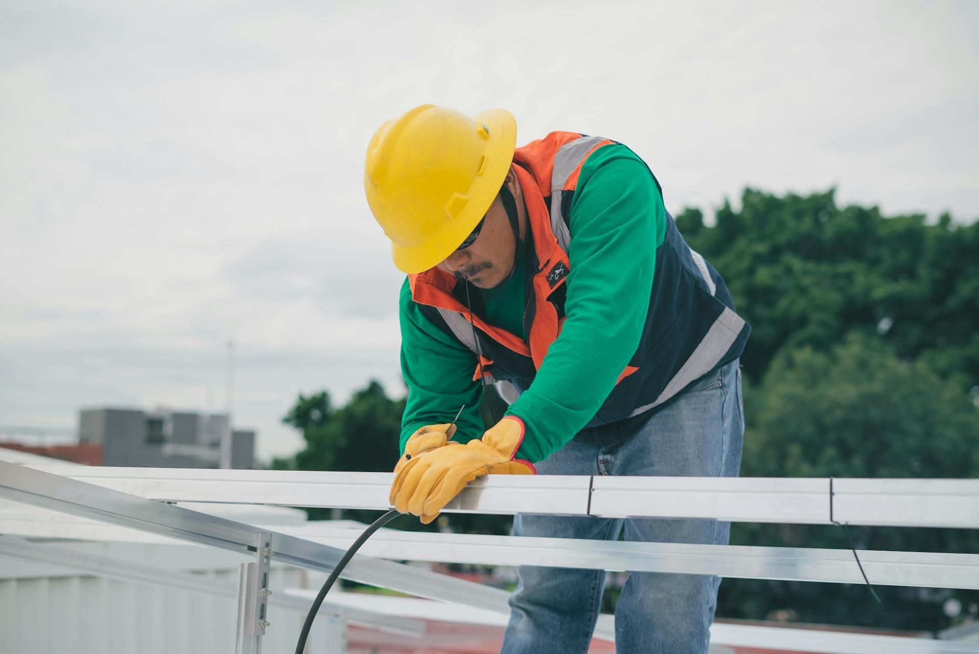 Electrician using a drill on an open electrical panel. Wires and components visible. Wearing a mask.