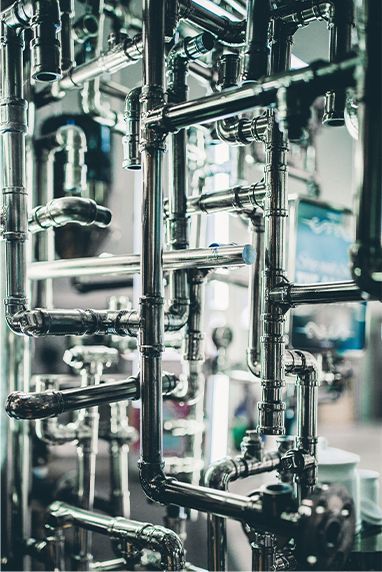 Complex network of shiny metal pipes in an industrial setting.