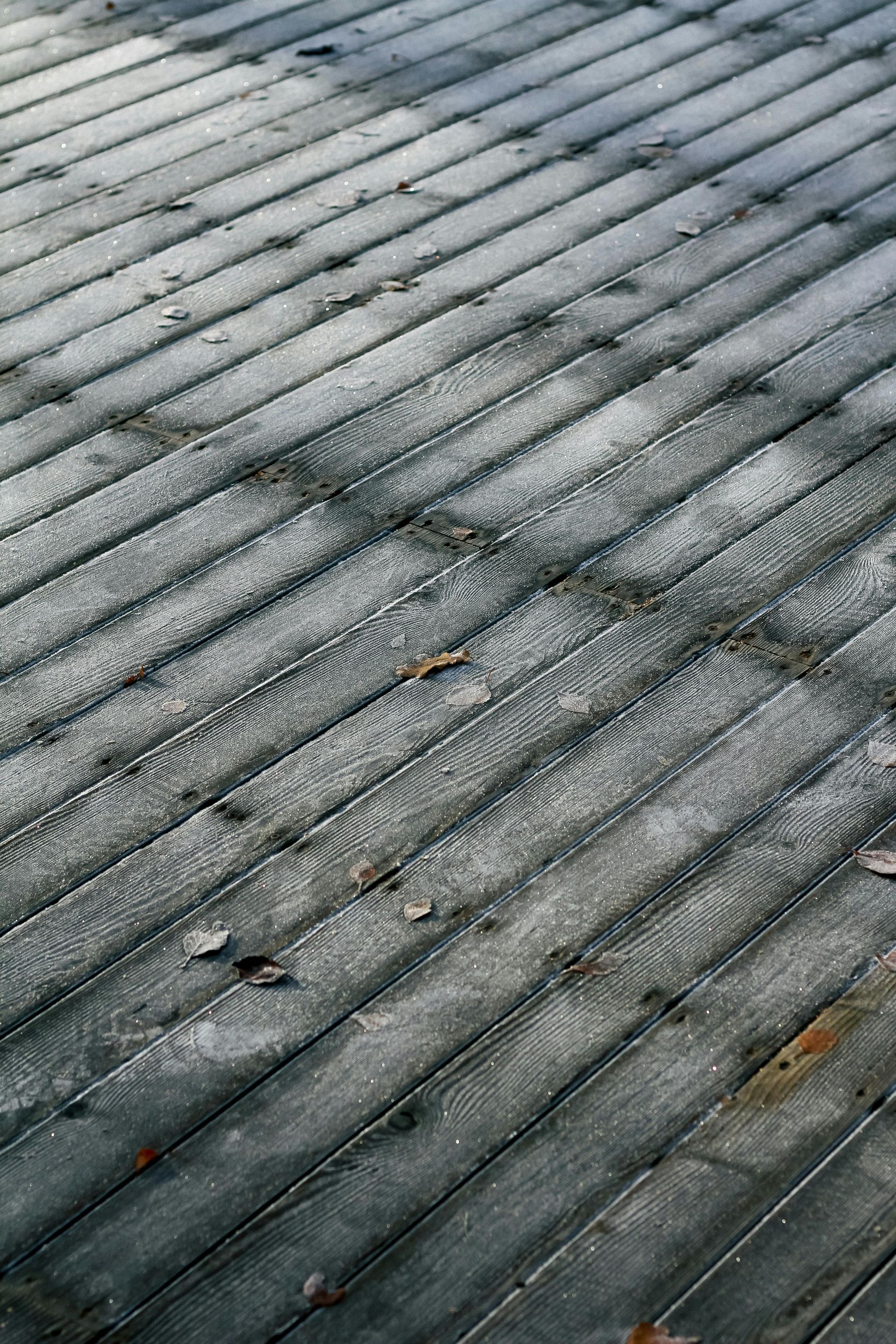 Wooden deck with diagonal planks covered in water or ice.