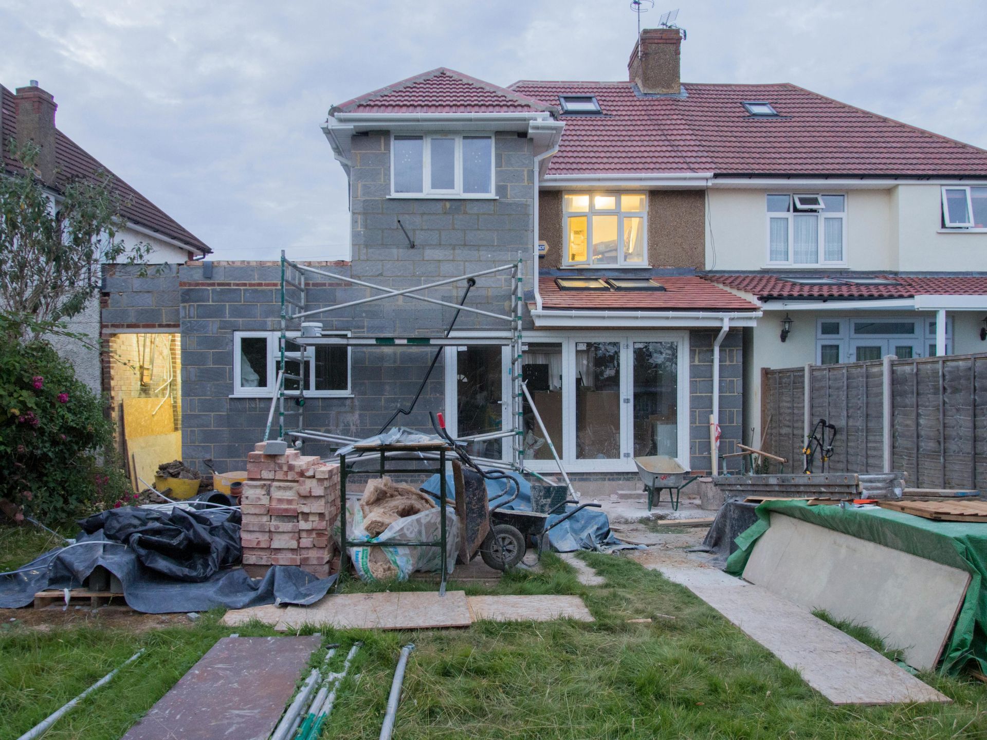 Rear of a house under construction; cinder block addition, scaffolding, French doors.