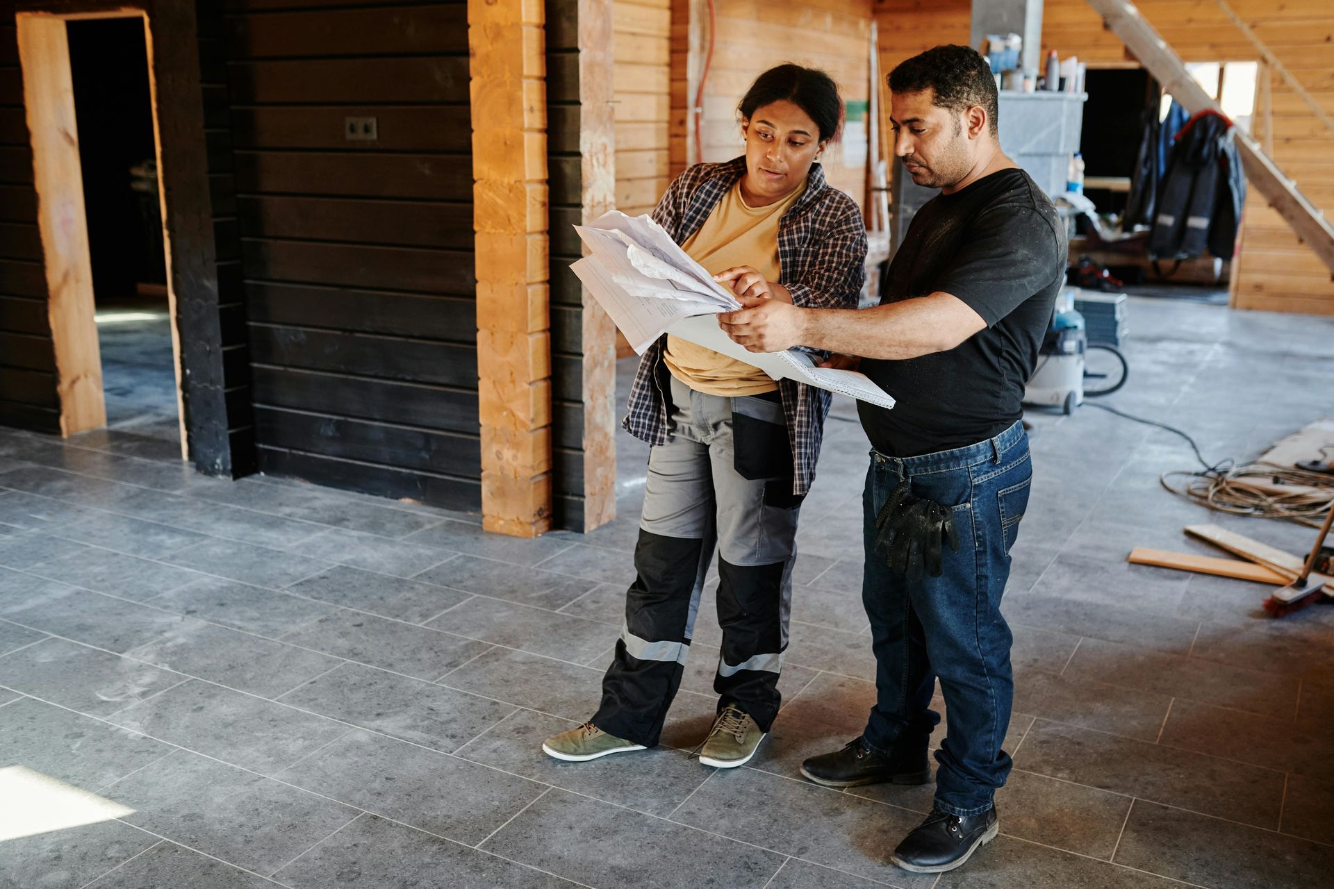 Two people reviewing blueprints in a building under construction.