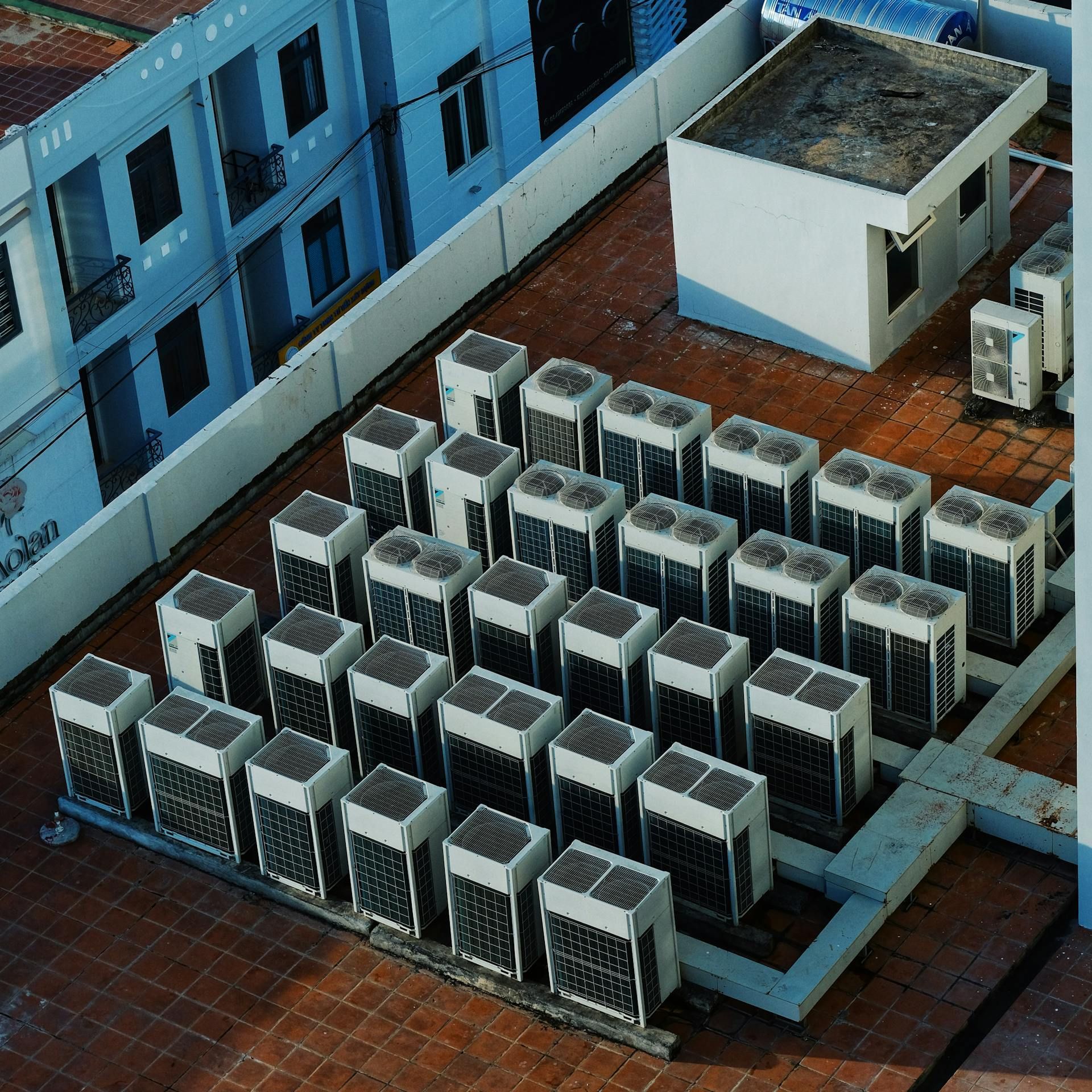 Rooftop with numerous satellite dishes, air conditioning units, and a building backdrop.