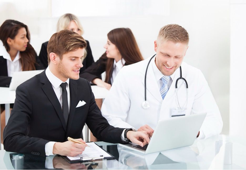 A doctor and a business professional collaborating on credentialing documents and insurance processe