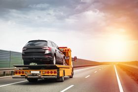 A car is being towed by a tow truck on a highway.