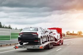 A car is being towed by a tow truck on a highway.