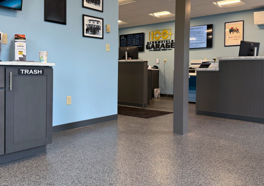 Interior of a business office with gray cabinets, light blue walls, and a speckled floor. | Bloomfield Garage