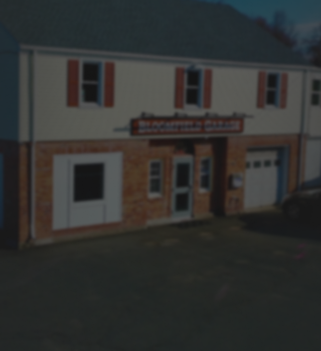 Two-story brick building with red shutters. Sign reads 