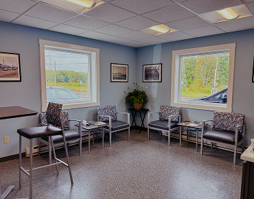Waiting area with gray chairs, windows, and potted plant. | Bloomfield Garage