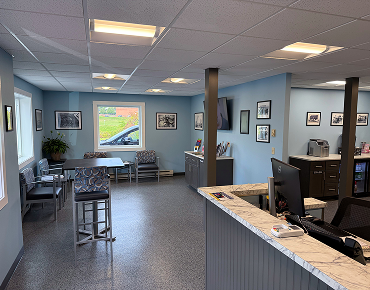 Waiting area with blue walls, gray flooring, seating, and a reception desk. | Bloomfield Garage