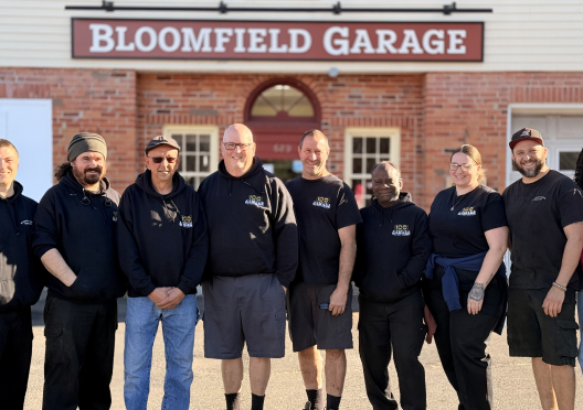 Group of people in front of Bloomfield Garage sign. | Bloomfield Garage