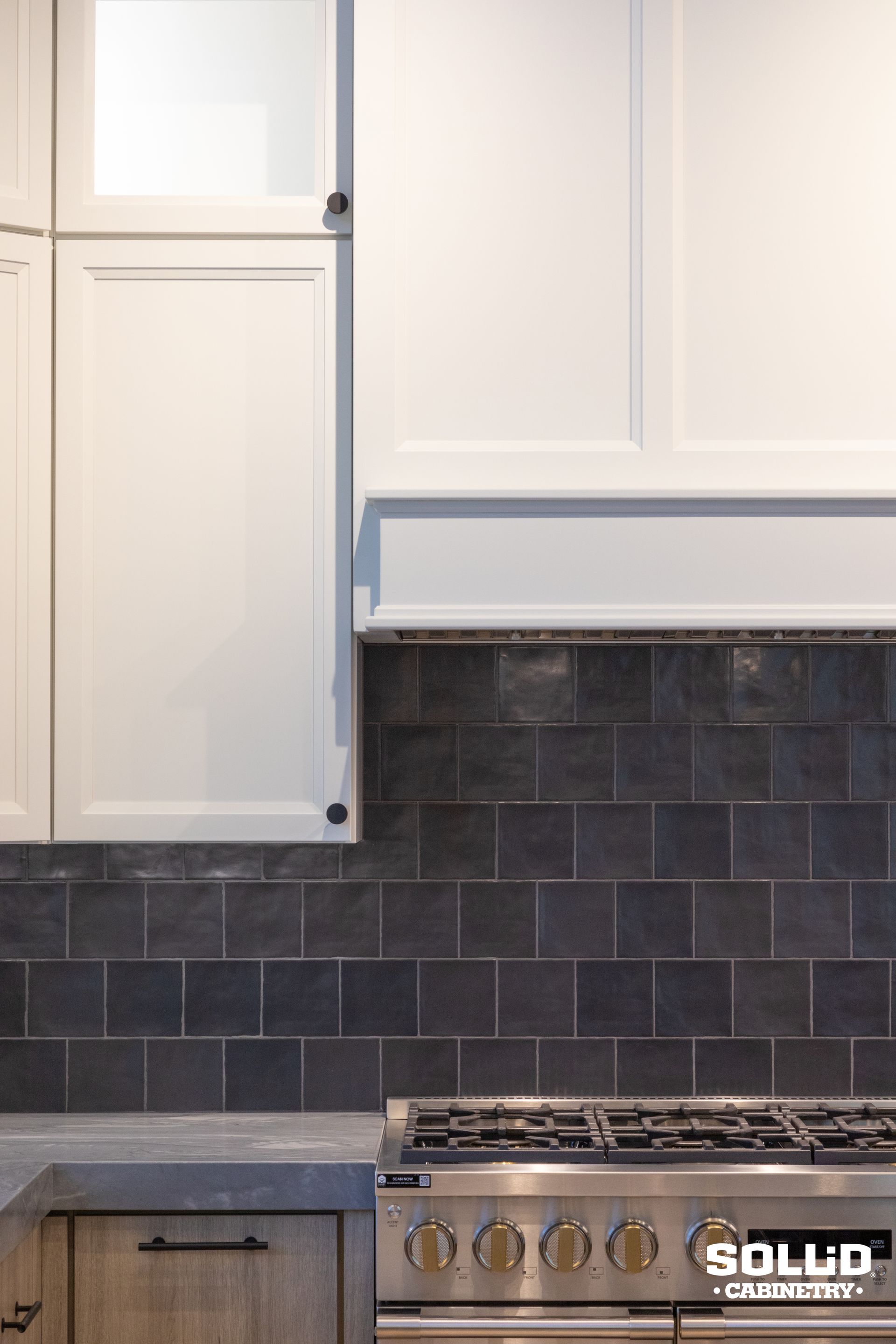 A kitchen with a stove top oven and white cabinets