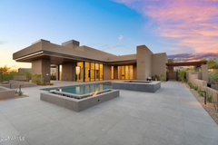 A large house in the desert with a driveway leading to it.